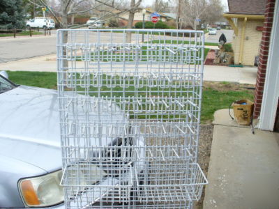 Rolling white metal spinner rack with hooks and baskets